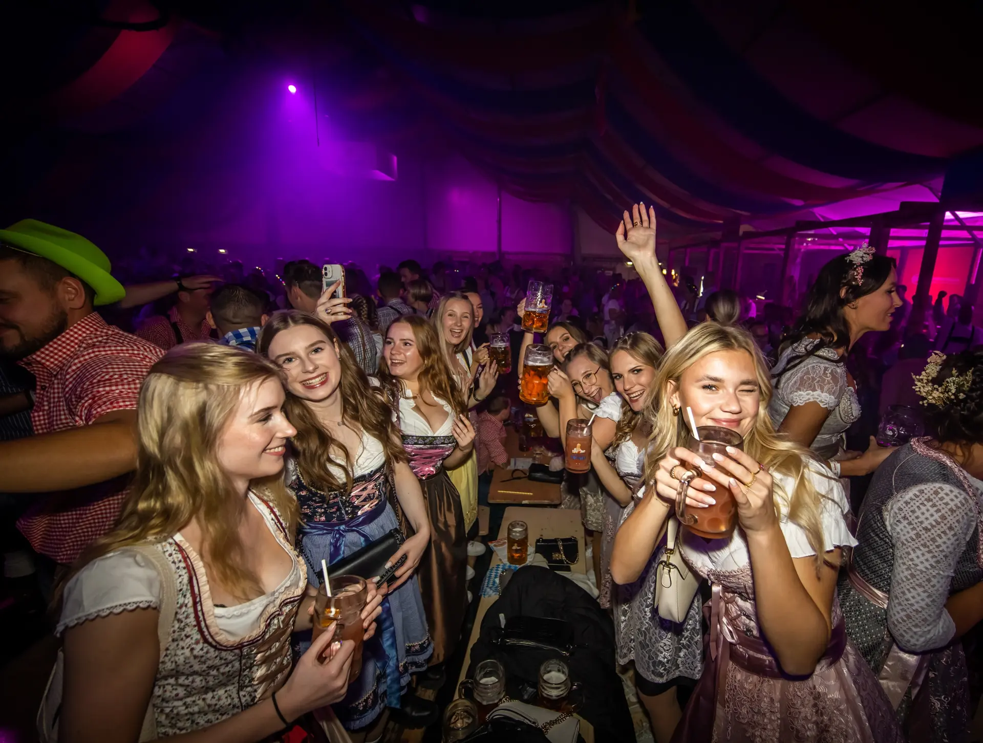 Eine Gruppe von jungen Frauen feiert ausgelassen in einem Festzelt.