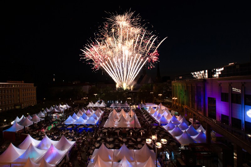Übersich über den Hansaplatz mit Marktständen im dunkeln, im Hintergrund Feuerwerk.