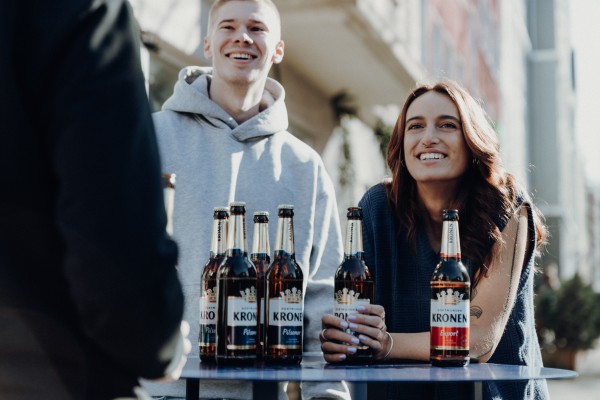 Ein Mann und eine Frau stehen lächelnd an einem Tisch mit Getränkeflaschen.