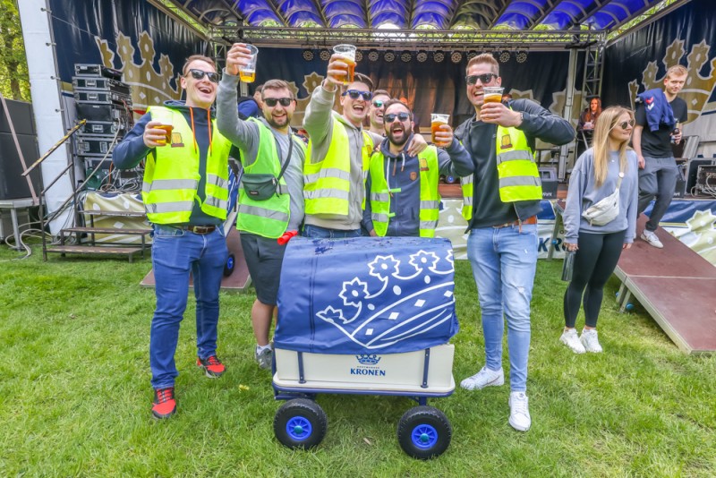 Eine Gruppe von jungen Erwachsenen genießt bei einem Outdoor-Event gemeinsam Getränke.