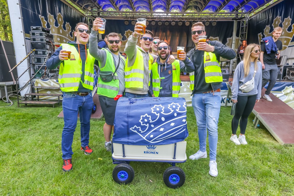 Eine Gruppe von jungen Erwachsenen genießt bei einem Outdoor-Event gemeinsam Getränke.