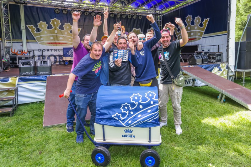 Mehrere Personen jubeln auf einer Bühne und präsentieren einen Wagen.