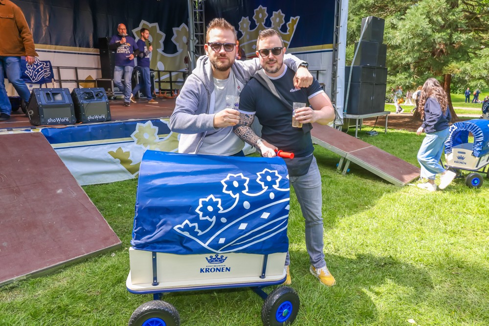 Zwei Männer stehen auf einer Veranstaltung im Freien neben einem dekorierten Wagen.