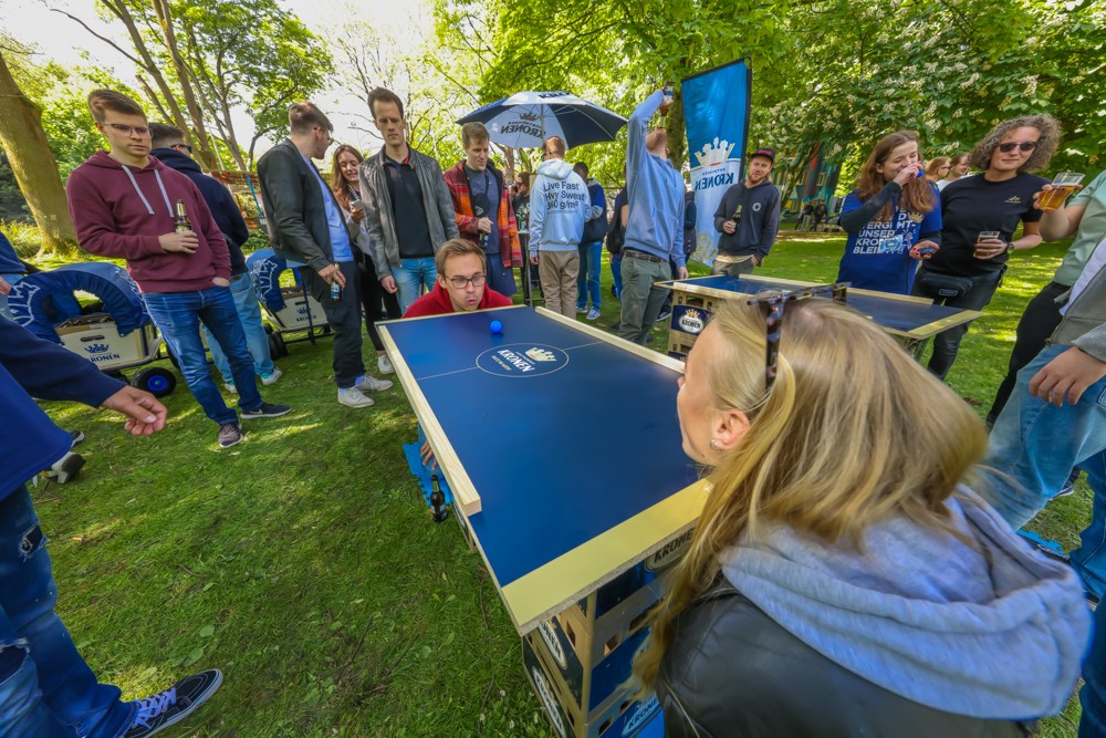 Eine junge Frau und ein junger Mann spielen Tischtennis draußen auf einer Veranstaltung.