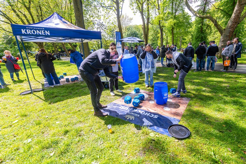 Eine Gruppe von Personen schockt mit einem Kronen Riesenwürfelspiel in einem Park.