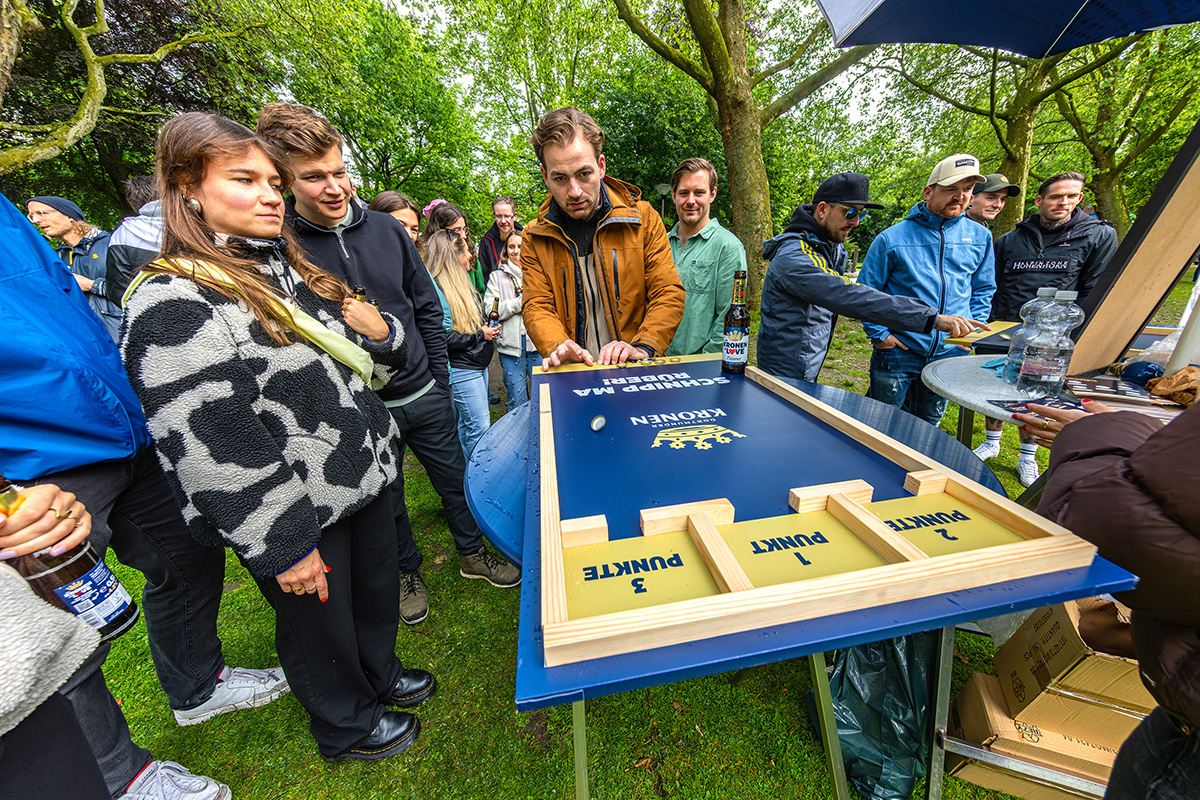 Mehrere Personen spielen in einem Park an einem Dortmunder Kronen Schnippspielbrett.